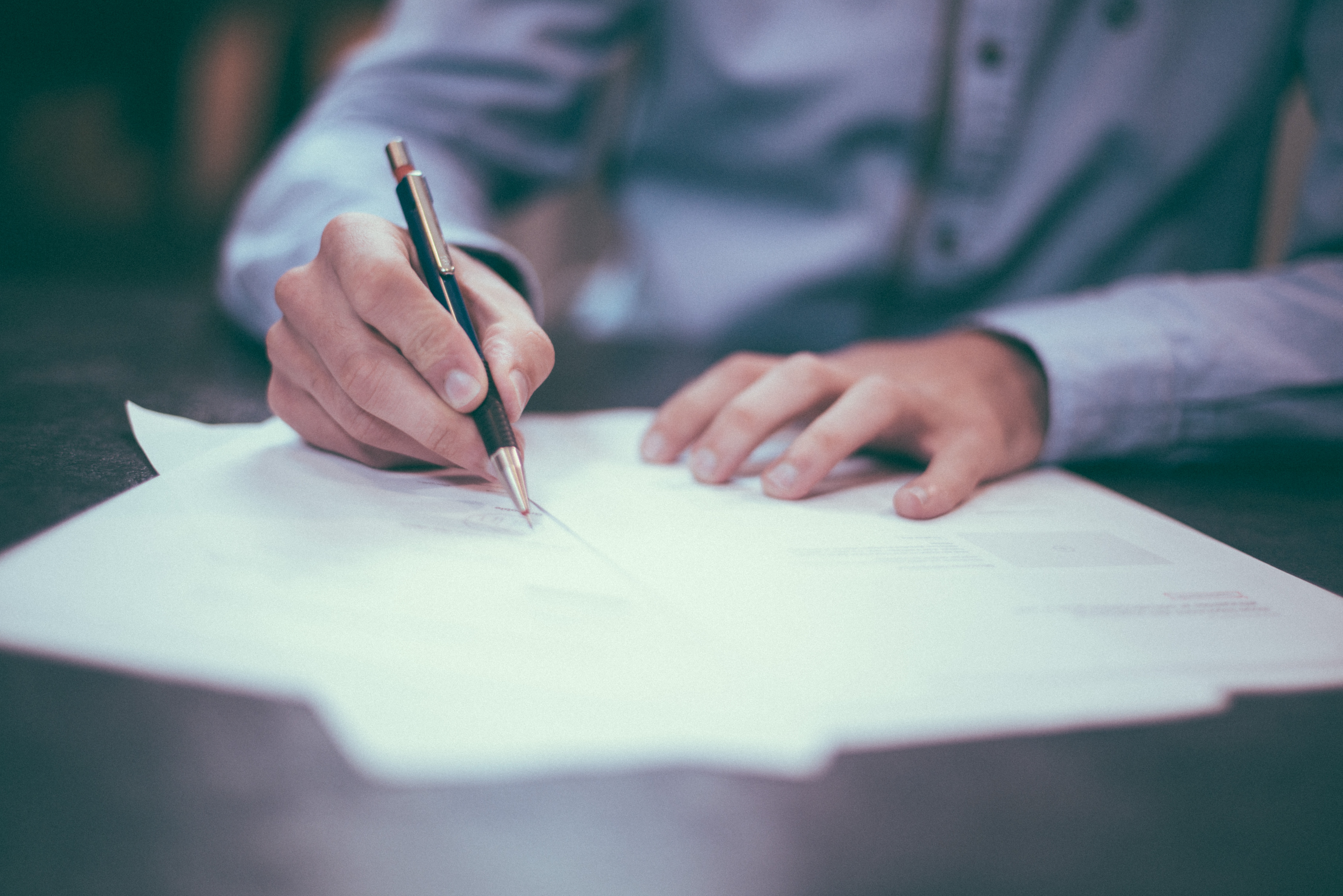 person using pen to write on paper