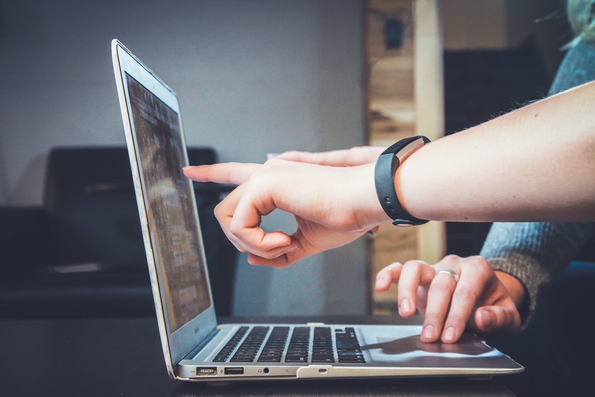 person pointing at laptop screen