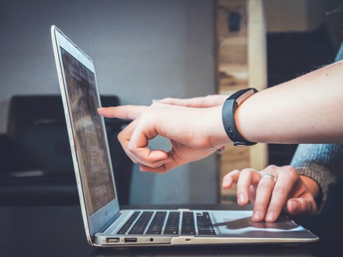 person pointing at laptop screen