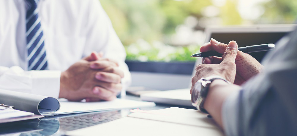 two people doing business with pens and notepads