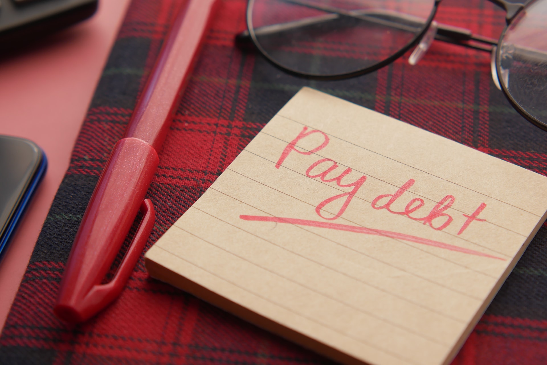 notepad with pay debt written in red pen