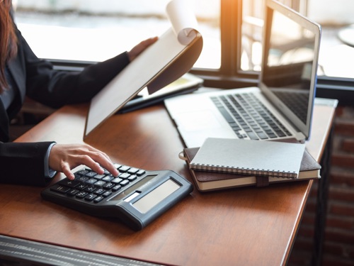 woman at desk with laptop and calculator