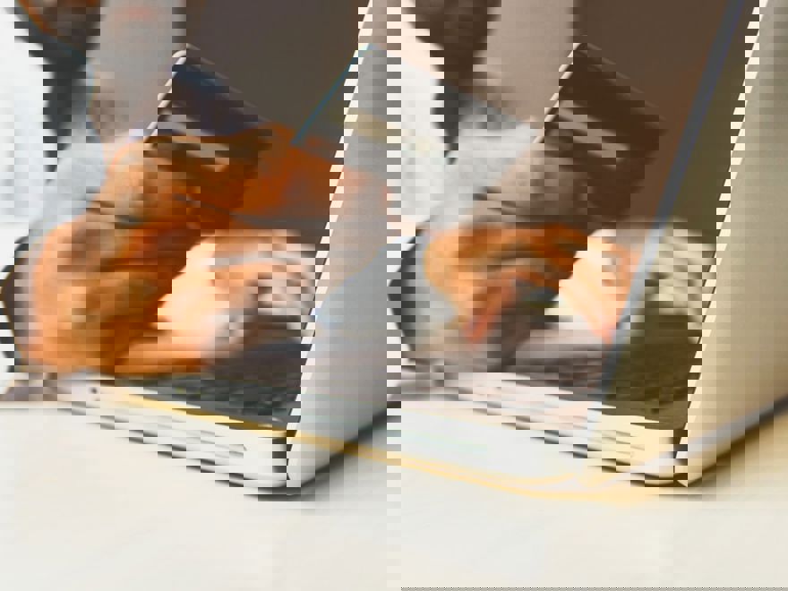 Person on laptop holding bank card